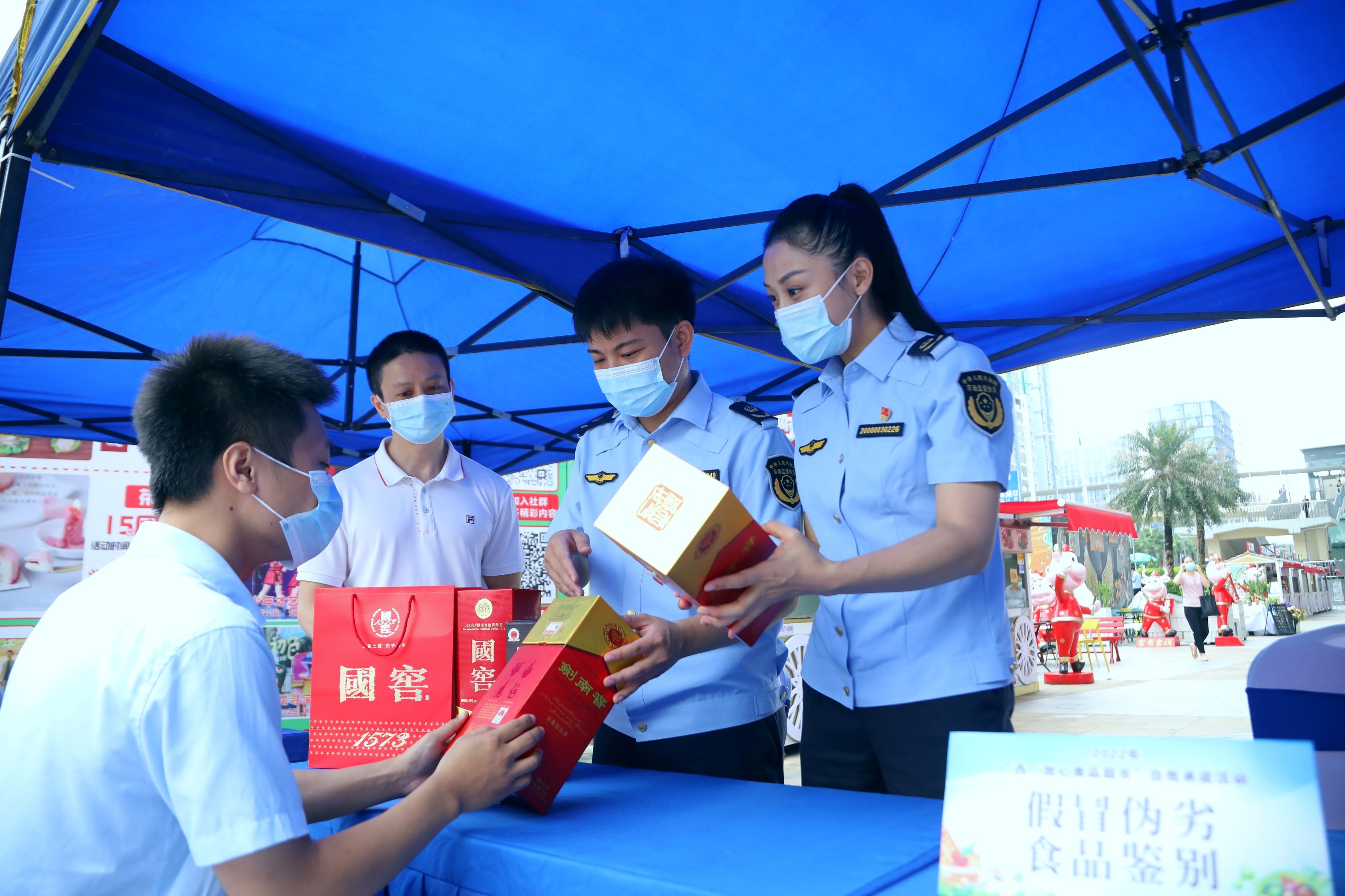 市场监管部门工作人员设置假冒伪劣食品真伪识别展示台，现场教消费者如何判断白酒真假。（何正君 摄）.jpg