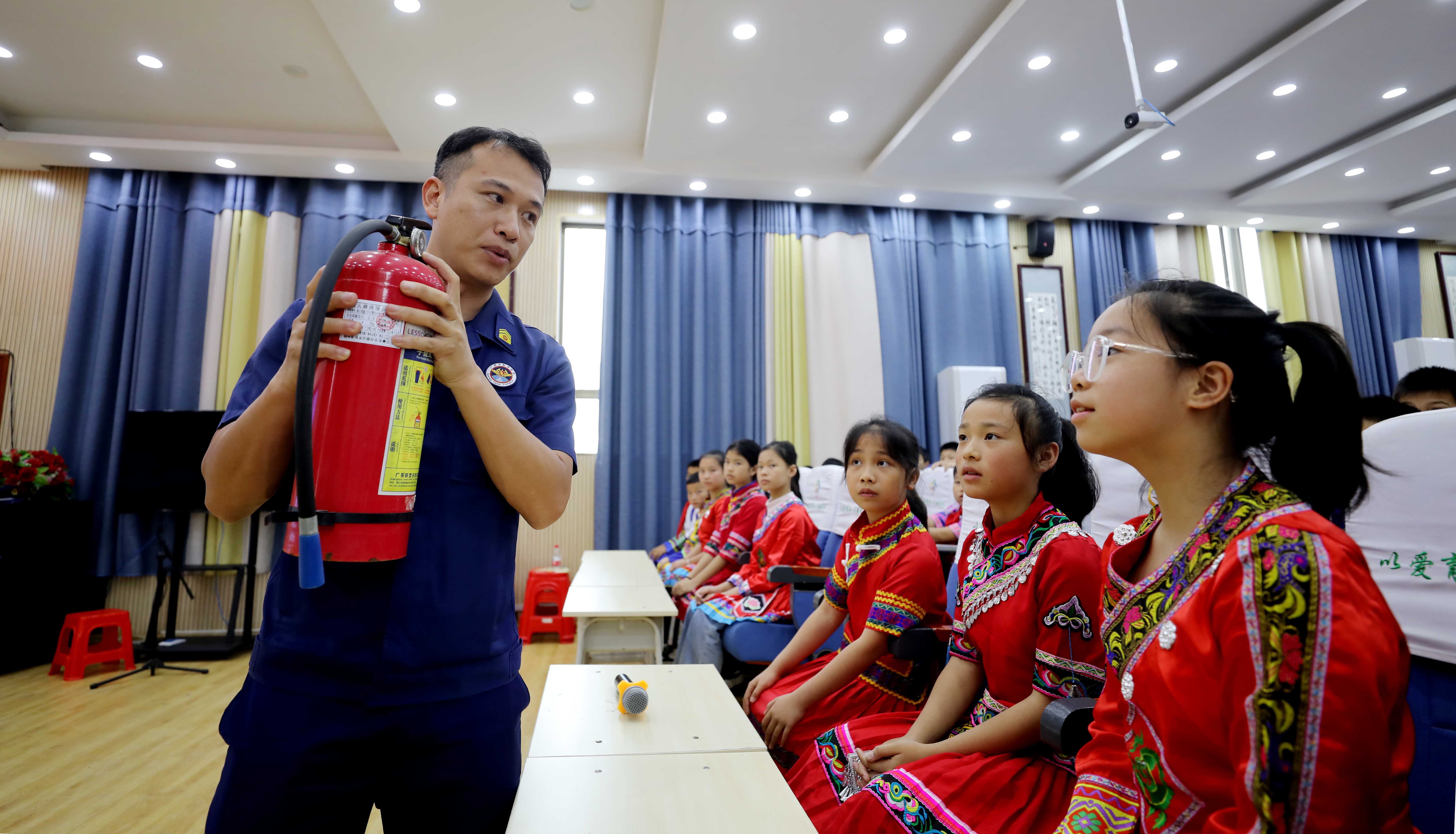 图1：5月10日，在广西柳州市融安县实验小学，消防员给少数民族学生讲解灭火器使用知识。（覃庆和 摄）.jpg