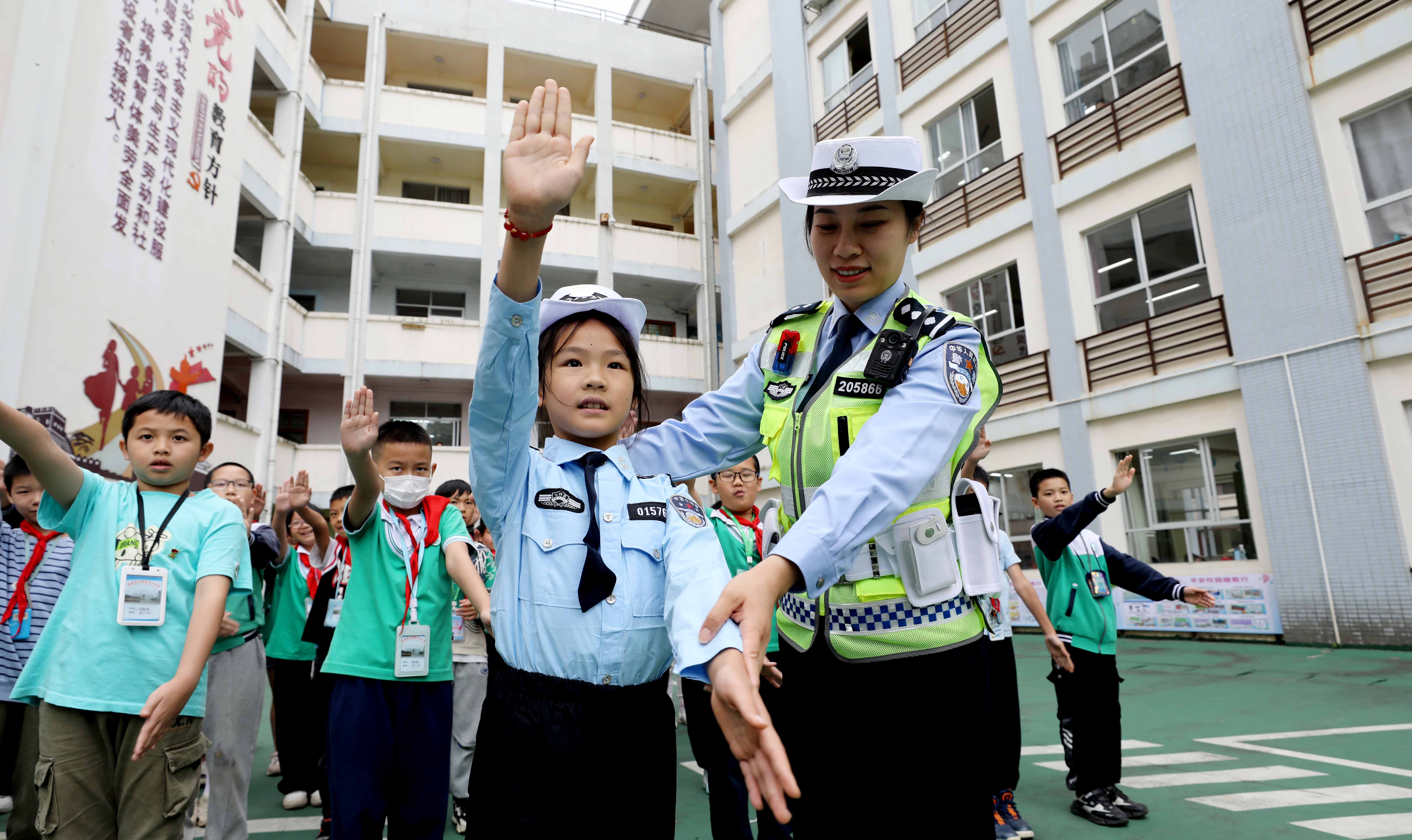 图8：5月22日，在广西柳州市融安县长安镇中心小学，民警在指导学生练习指示手势。（覃庆和 摄）.jpg