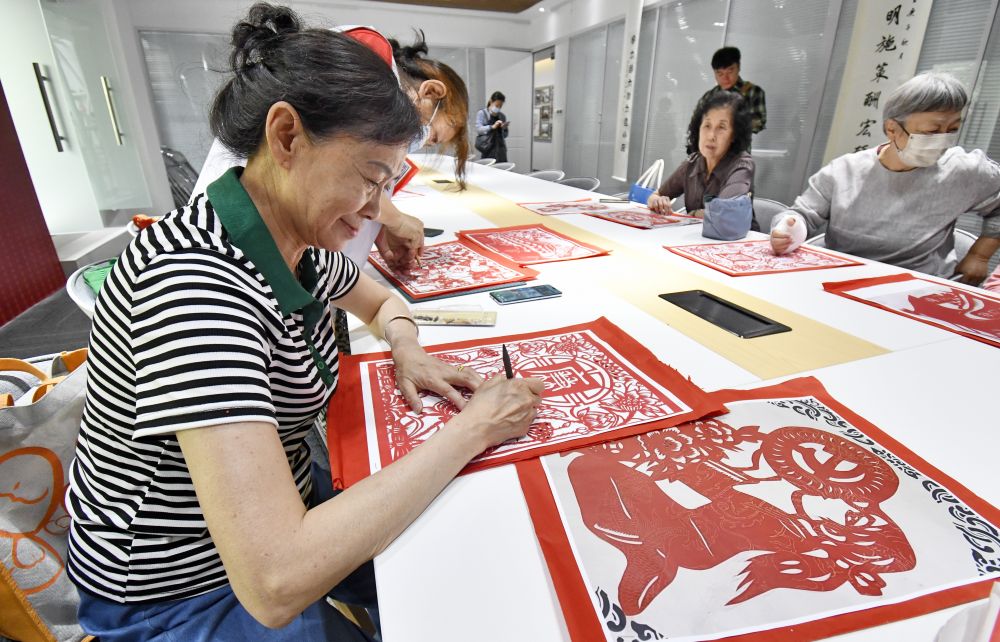北京朝阳无限社区的老年人在社区养老驿站参加剪纸活动（2023年5月17日摄）。新华社记者 李欣 摄.jpeg